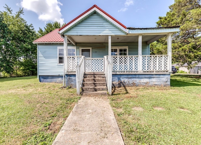 bungalow-style home featuring a front lawn, covered porch, and metal roof