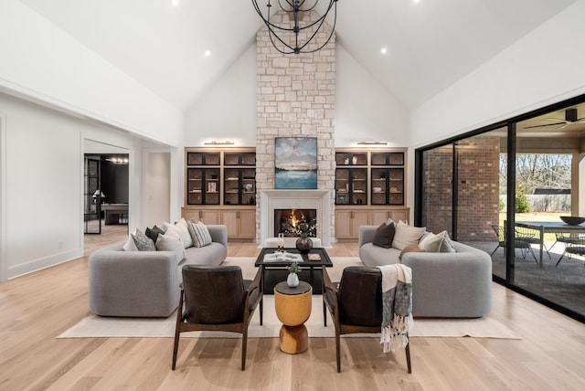 living area with a stone fireplace, wood finished floors, a chandelier, and high vaulted ceiling