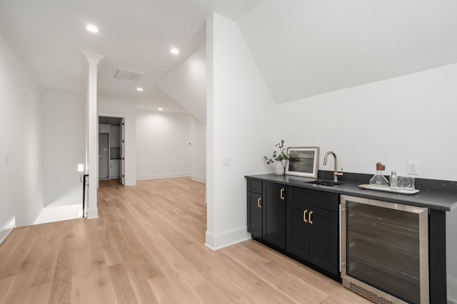 bar with visible vents, beverage cooler, light wood-type flooring, indoor wet bar, and a sink