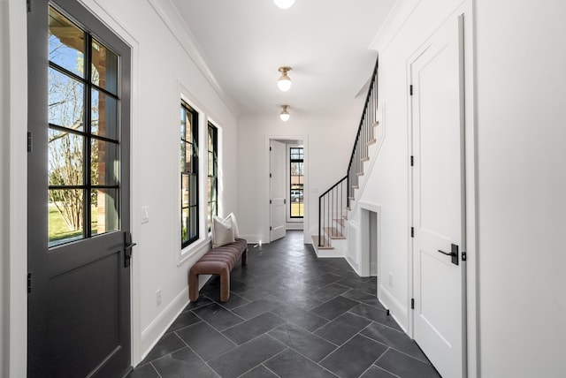 entryway featuring crown molding, stairway, plenty of natural light, and baseboards