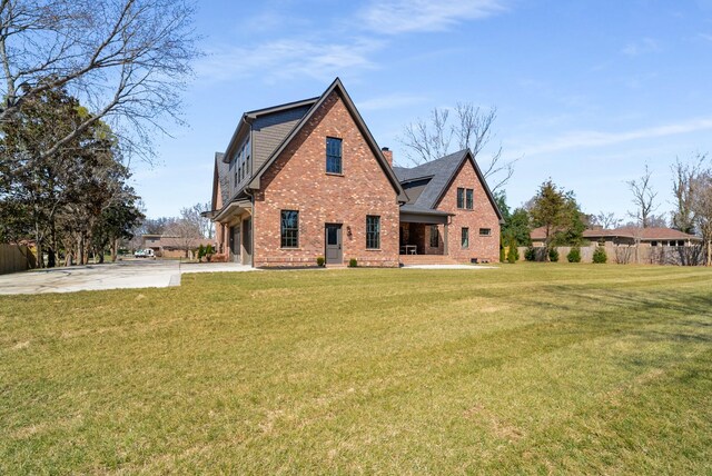 back of property with brick siding, a chimney, and a lawn