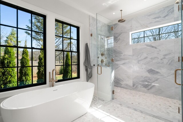 bathroom featuring a marble finish shower and a soaking tub