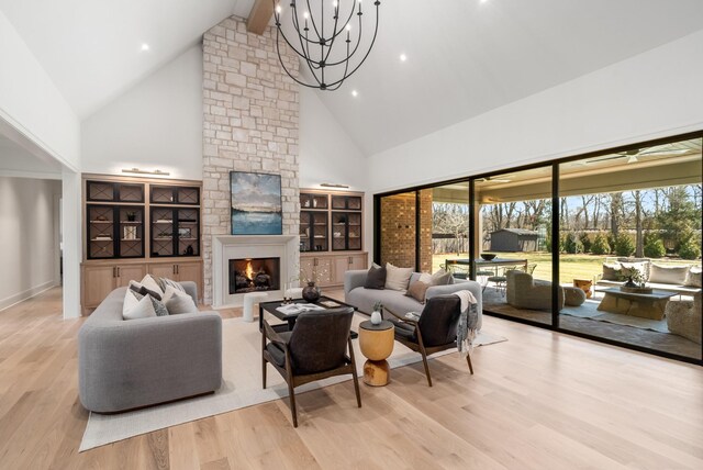 living area featuring a stone fireplace, a notable chandelier, wood finished floors, and high vaulted ceiling