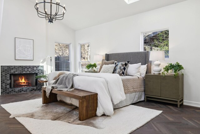 bedroom featuring a tiled fireplace, a notable chandelier, baseboards, and high vaulted ceiling