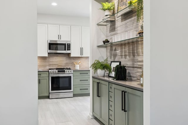 kitchen featuring green cabinetry, open shelves, stainless steel appliances, white cabinetry, and tasteful backsplash