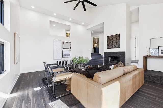 living room featuring baseboards, recessed lighting, a fireplace, wood finished floors, and high vaulted ceiling