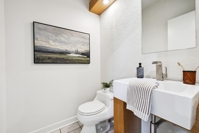 half bath featuring tile patterned flooring, toilet, baseboards, and a sink