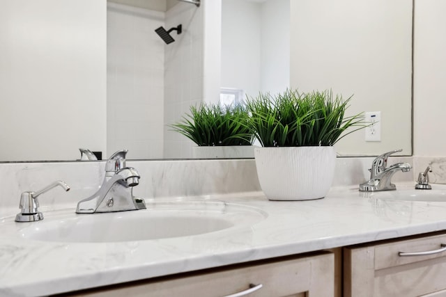 full bathroom featuring a sink, double vanity, and a tile shower