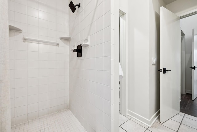 full bathroom featuring tile patterned floors, baseboards, and tiled shower