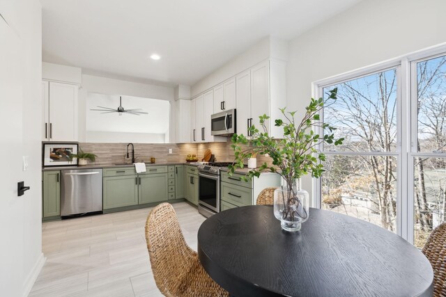 kitchen featuring green cabinetry, stainless steel appliances, white cabinets, and decorative backsplash