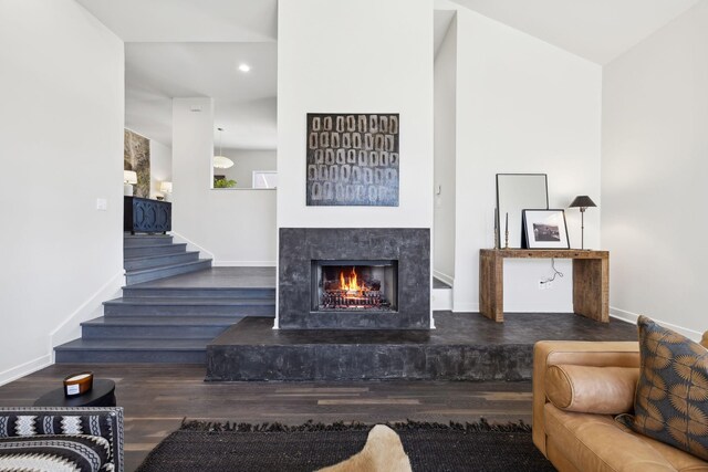 living room with stairs, baseboards, wood finished floors, and a fireplace