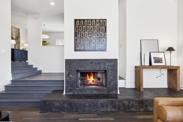 living room with a premium fireplace, baseboards, wood finished floors, and stairs