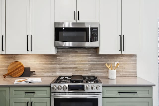 kitchen featuring green cabinetry, stainless steel appliances, white cabinetry, dark countertops, and tasteful backsplash