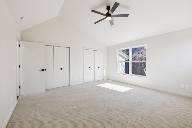 unfurnished bedroom featuring a ceiling fan, carpet, multiple closets, and high vaulted ceiling