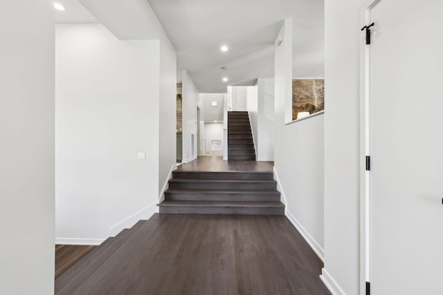 corridor featuring recessed lighting, baseboards, dark wood finished floors, and stairs