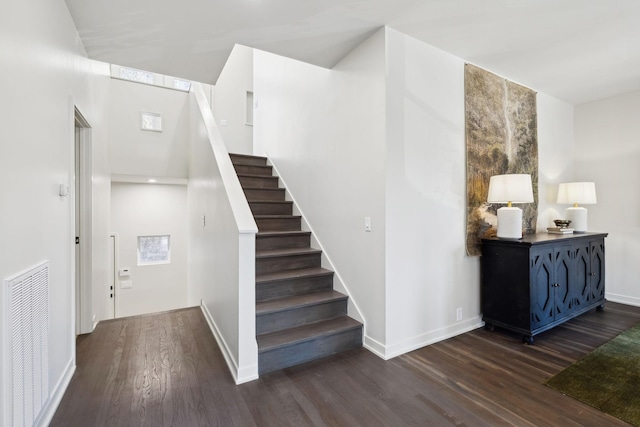 stairway with visible vents, baseboards, and wood finished floors