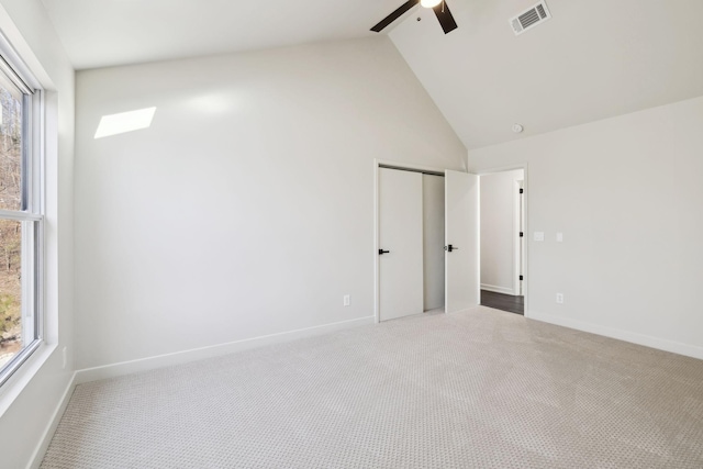 carpeted empty room featuring visible vents, high vaulted ceiling, baseboards, and a ceiling fan