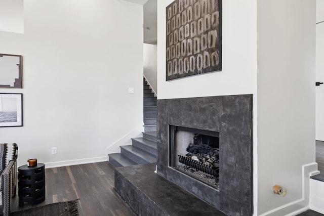 living area with stairway, baseboards, wood finished floors, and a fireplace