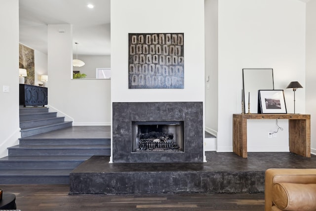 living room with a high end fireplace, stairs, baseboards, and wood finished floors