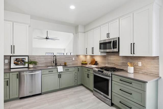 kitchen featuring a sink, decorative backsplash, appliances with stainless steel finishes, and green cabinets