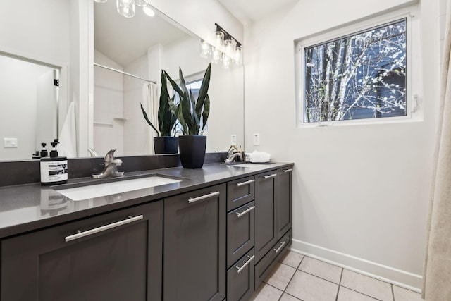 bathroom with a shower with shower curtain, baseboards, double vanity, a sink, and tile patterned floors