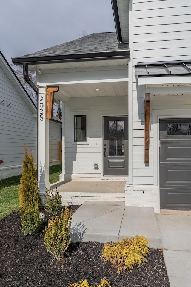 entrance to property featuring a garage, a porch, and a shingled roof