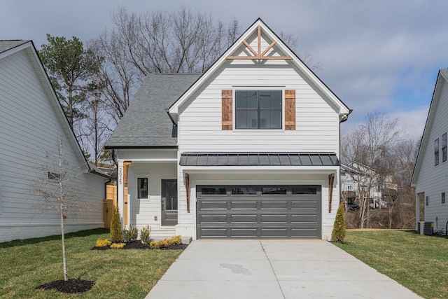 view of front of house featuring concrete driveway, roof with shingles, a front yard, metal roof, and a standing seam roof