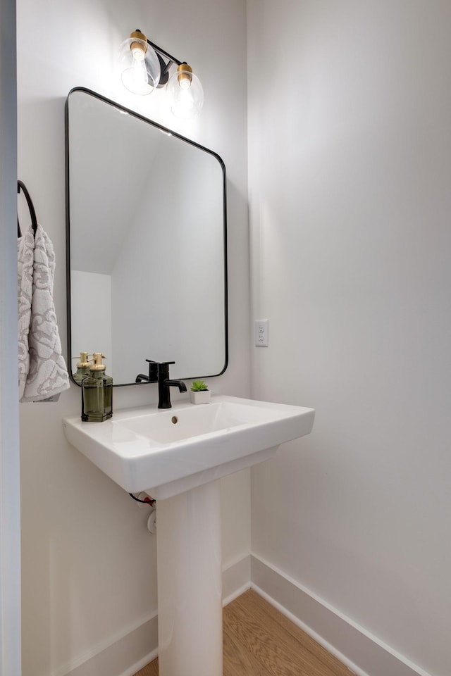 bathroom with wood finished floors, baseboards, and a sink