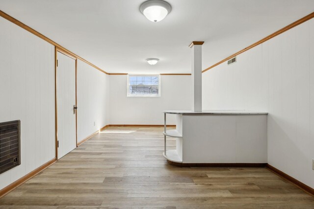 basement featuring light wood-style flooring, heating unit, and baseboards