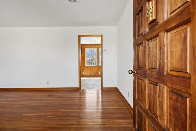 spare room featuring baseboards and dark wood-style floors