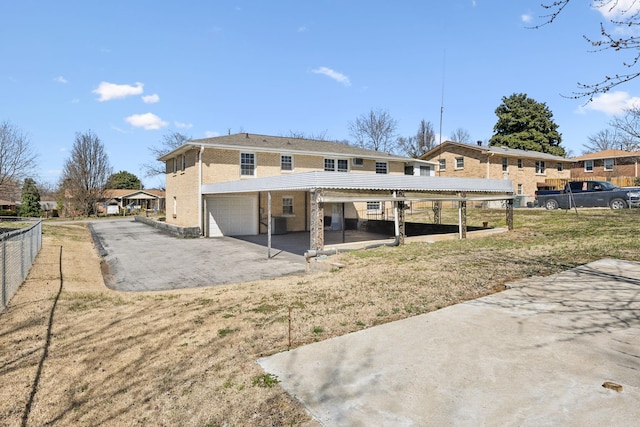 back of property featuring driveway, fence, a garage, brick siding, and a patio area