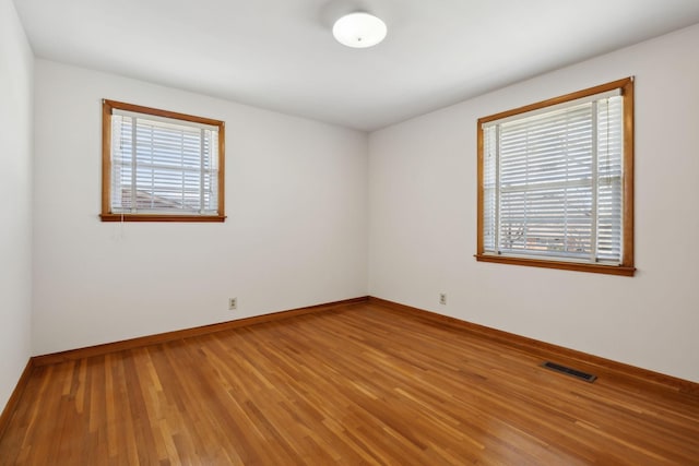 unfurnished room with visible vents, light wood-style flooring, and baseboards