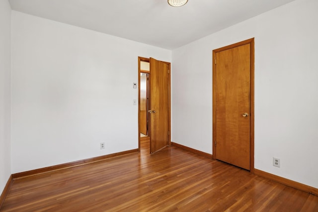 unfurnished room with baseboards and wood finished floors