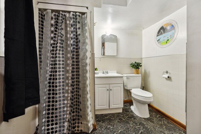 full bathroom with toilet, marble finish floor, curtained shower, tile walls, and vanity