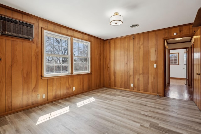 spare room with wooden walls, visible vents, baseboards, wood finished floors, and a wall mounted AC