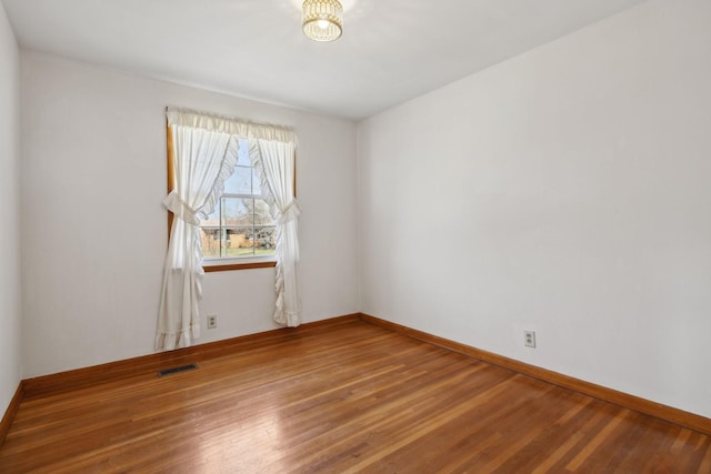 spare room with visible vents, baseboards, and wood finished floors