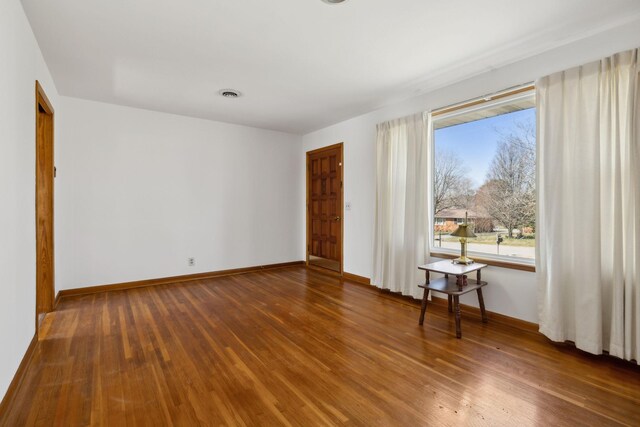 spare room featuring visible vents, baseboards, and wood finished floors