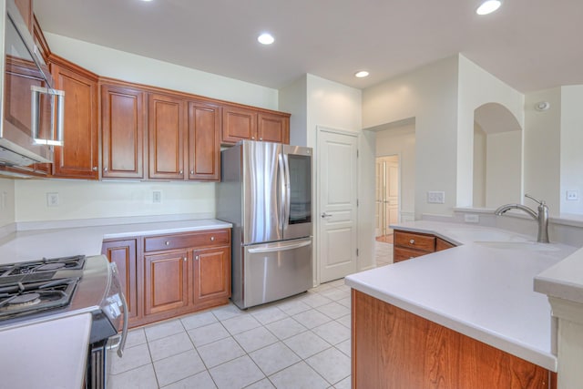 kitchen featuring brown cabinets, stainless steel appliances, light countertops, and a sink