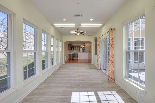 unfurnished sunroom with a ceiling fan and visible vents