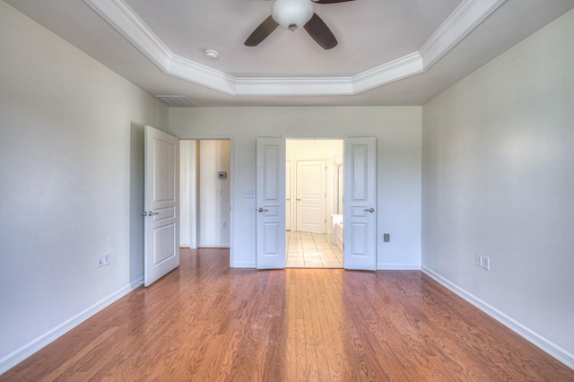 unfurnished bedroom with baseboards, a raised ceiling, wood finished floors, and ornamental molding