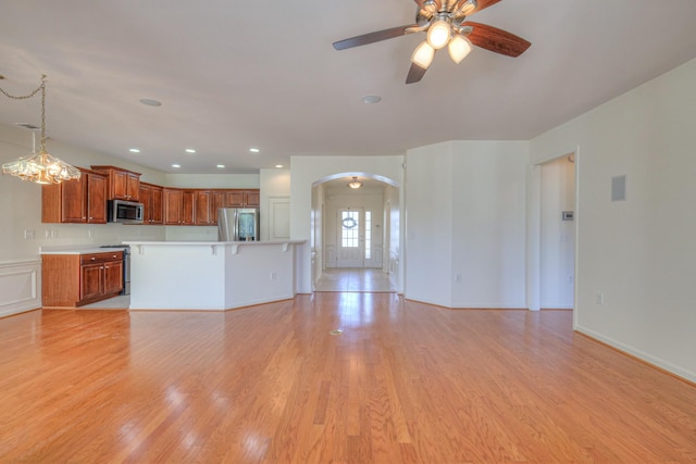 unfurnished living room featuring light wood-style flooring, recessed lighting, a ceiling fan, and arched walkways