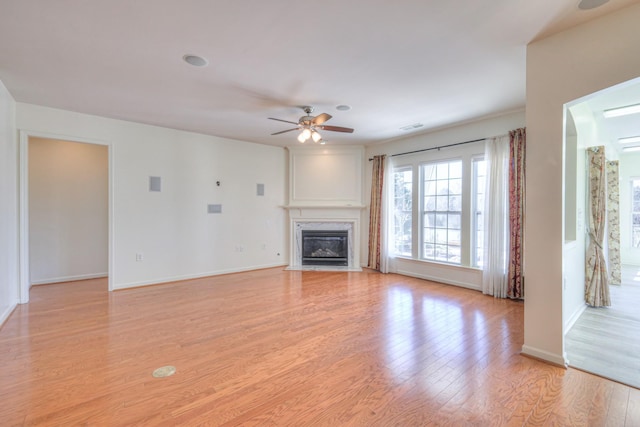 unfurnished living room with baseboards, visible vents, light wood finished floors, a fireplace, and ceiling fan