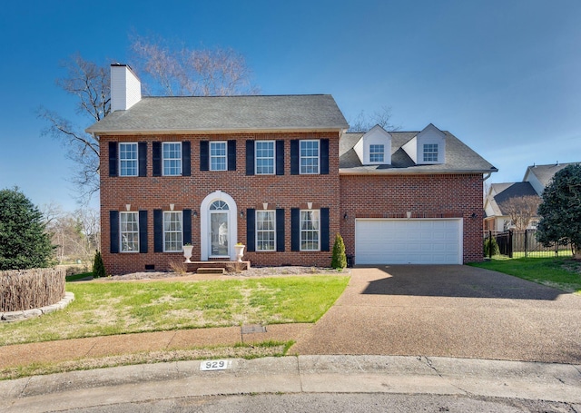 colonial home with brick siding, an attached garage, fence, a front yard, and driveway