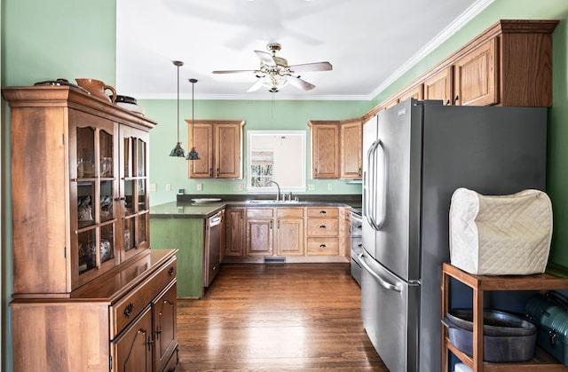 kitchen with dark countertops, ornamental molding, appliances with stainless steel finishes, and a sink