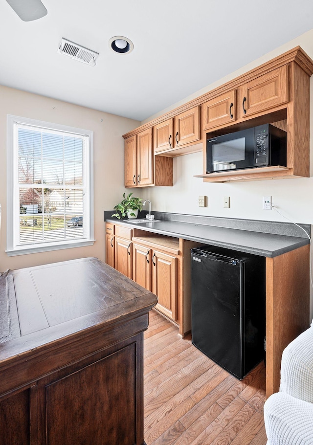 kitchen featuring dark countertops, visible vents, light wood-style flooring, black microwave, and fridge