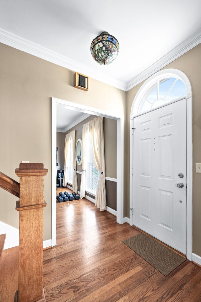 foyer entrance featuring baseboards, wood finished floors, visible vents, and ornamental molding