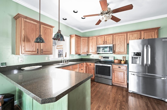 kitchen featuring ornamental molding, a sink, dark countertops, appliances with stainless steel finishes, and a peninsula