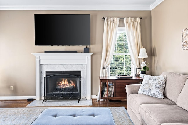 living room featuring a premium fireplace, baseboards, wood finished floors, and crown molding