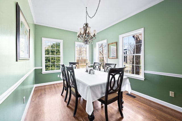 dining room featuring visible vents, wood finished floors, crown molding, baseboards, and a chandelier