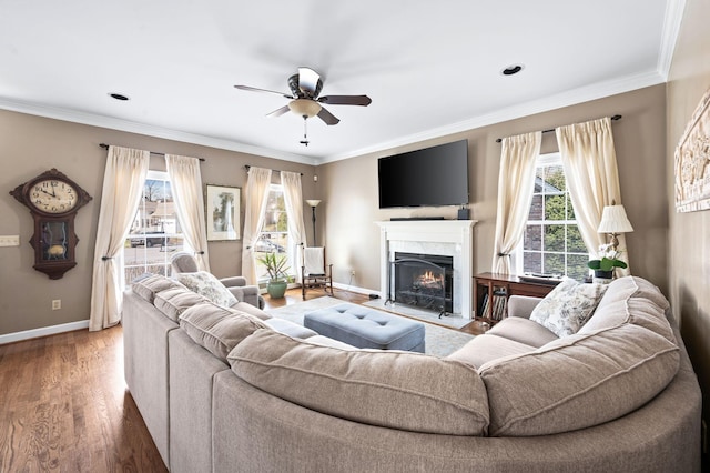 living area featuring a high end fireplace, crown molding, baseboards, and wood finished floors